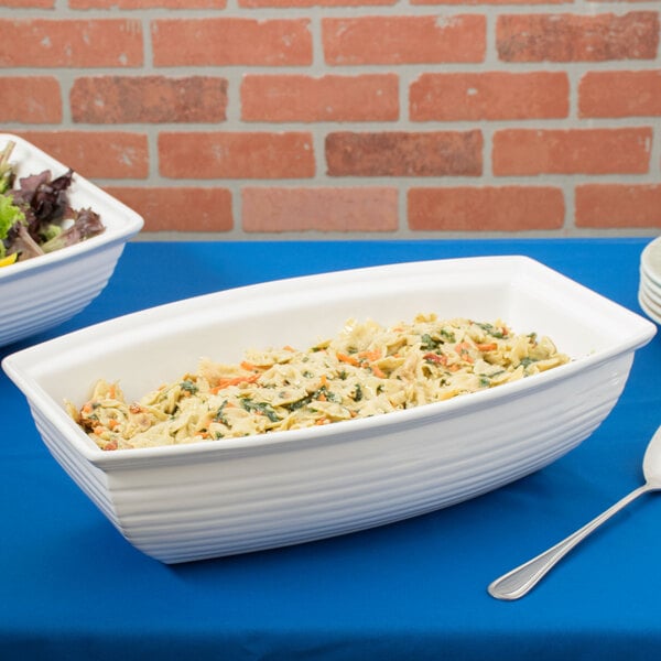 A white Tablecraft cast aluminum salad bowl filled with pasta and salad on a table.