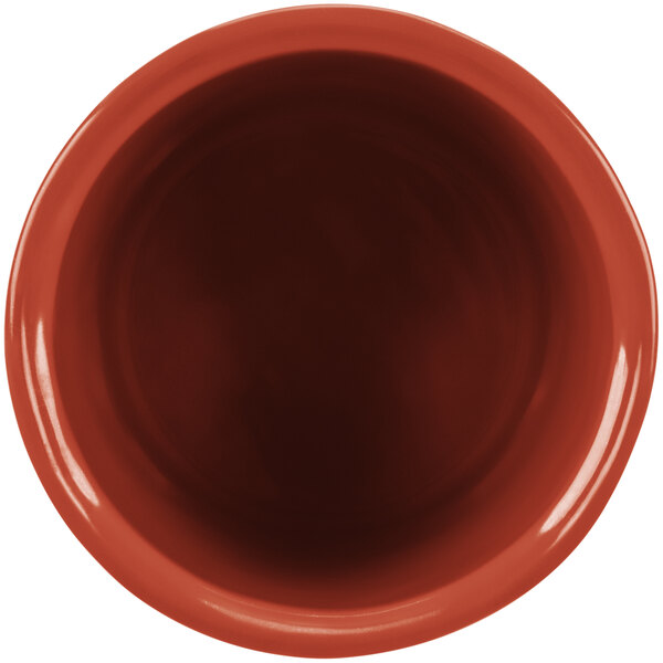 A close-up of a red Tablecraft salad dressing bowl with a brown rim.