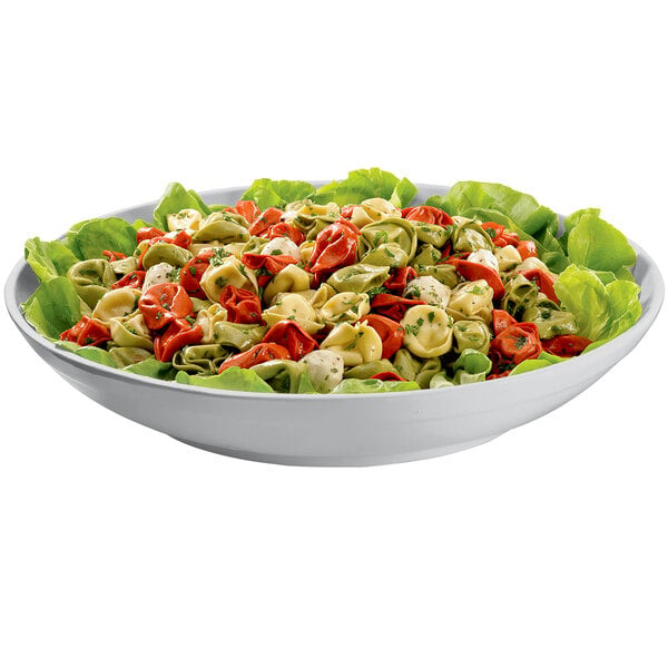 A Tablecraft natural cast aluminum pasta bowl filled with pasta and lettuce, red and green tortellini, and green and red tomatoes.