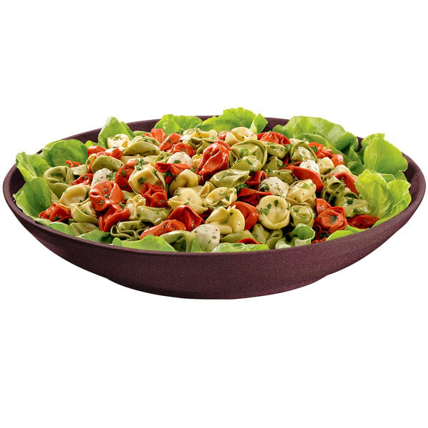 A maroon speckled cast aluminum bowl filled with pasta and lettuce.