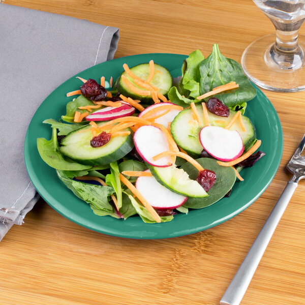 A Carlisle meadow green melamine salad plate with salad on it.