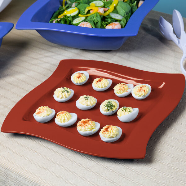 A Tablecraft square copper cast aluminum platter with deviled eggs and salad on a table.