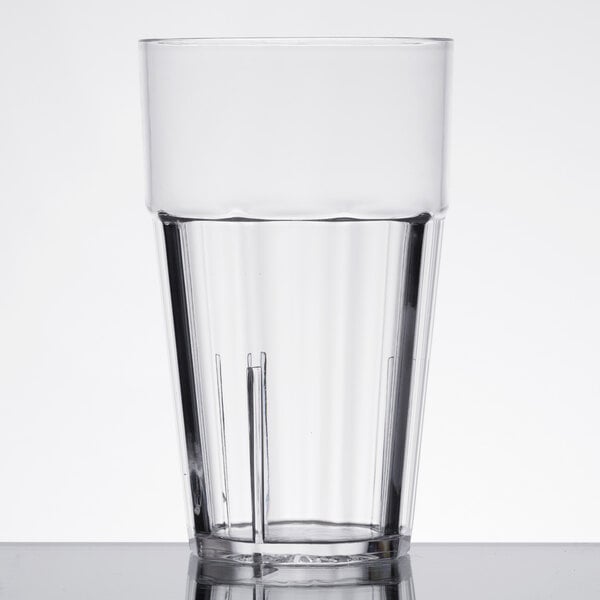 A close-up of a Thunder Group clear polycarbonate tumbler filled with water on a table.