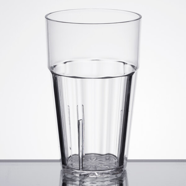 A close-up of a Thunder Group clear polycarbonate tumbler with water in it on a table.