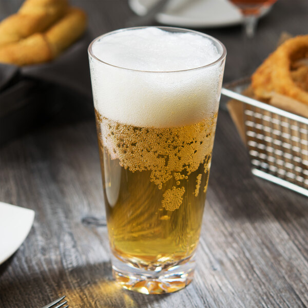 A Thunder Group plastic mixing glass filled with beer on a table with food.