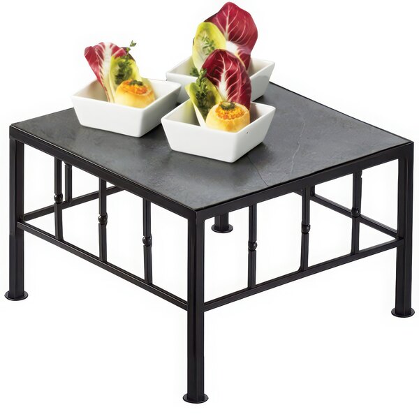 A black Cal-Mil square riser with slate top holding food on a table.