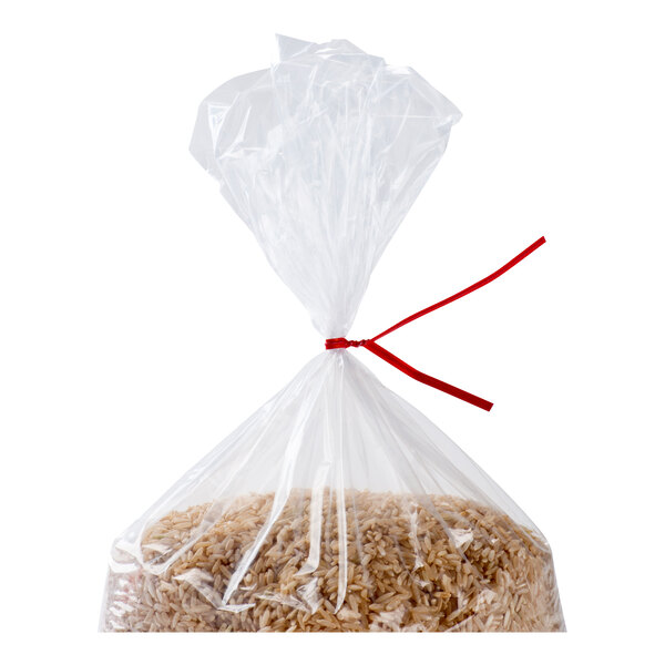 A clear plastic bag filled with brown rice, tied at the top with a red twist tie.