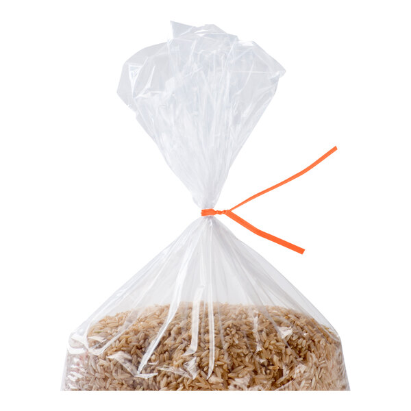 A clear plastic bag filled with brown rice, tied at the top with an orange twist tie.