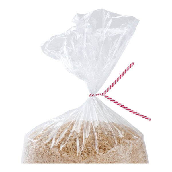 A clear plastic bag filled with rice, tied at the top with a red and white striped twist tie.