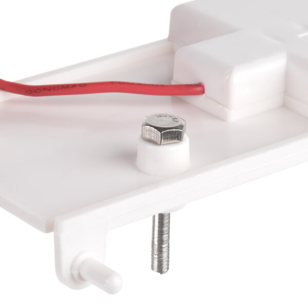 A white plastic device with a red wire.