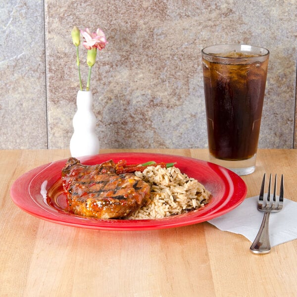 A red Sensation melamine plate with food and a drink on a table.