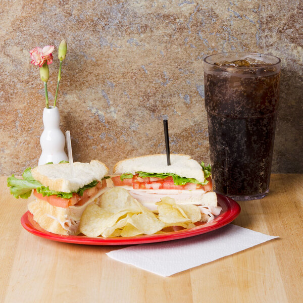 A red oval platter with sandwiches and chips on a table.