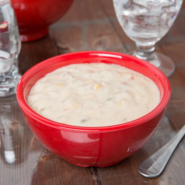 A bowl of soup in a red GET Sensation bowl on a table.