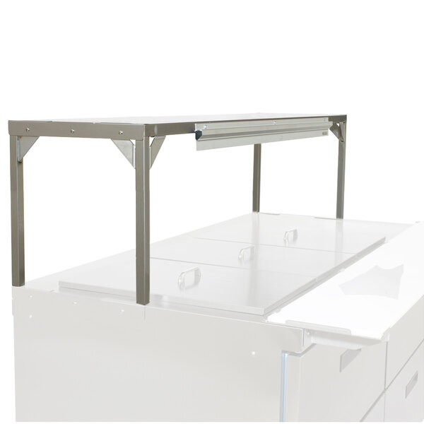 A white table with a stainless steel Delfield single overshelf on top.
