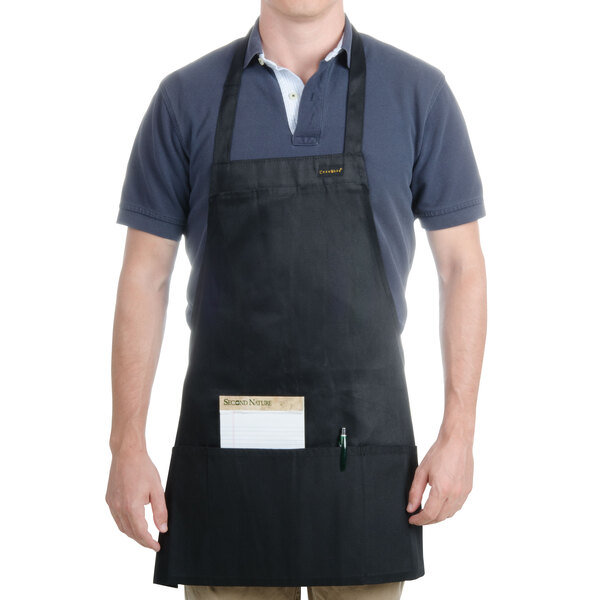 A man wearing a black Chef Revival bib apron with a pocket.