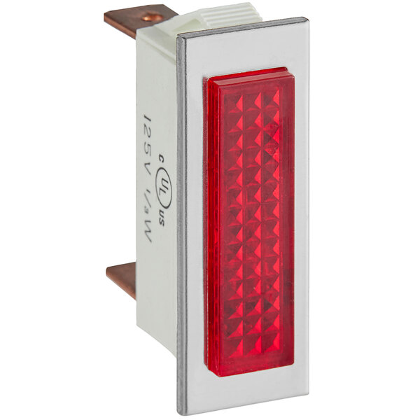 A close-up of a red rectangular pilot light with copper corners.