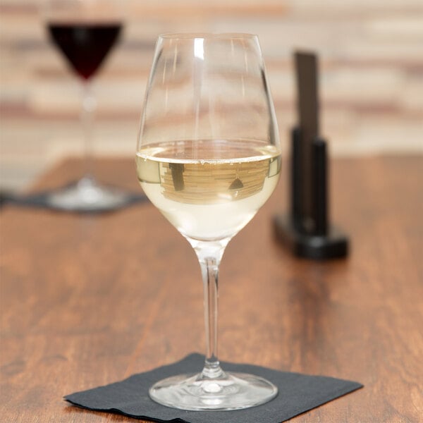 A Spiegelau Authentis white wine glass sits on a table with white wine in it.