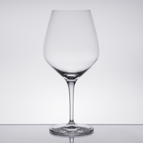 A Spiegelau Authentis burgundy wine glass on a table with a reflection.