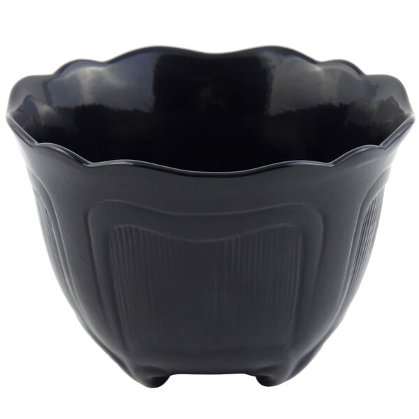 A black bowl with a scalloped edge and large handle.