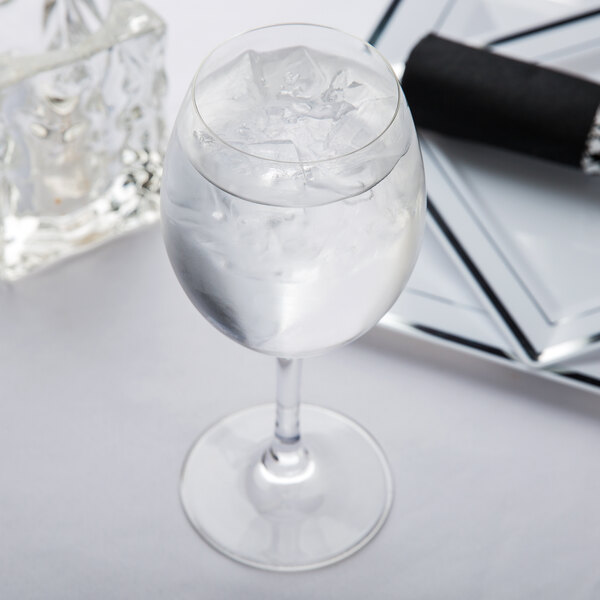 A Spiegelau red wine glass filled with ice water on a white background.