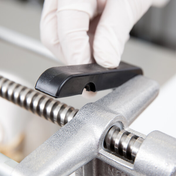 A person in gloves using a screwdriver to install a black metal support rod.