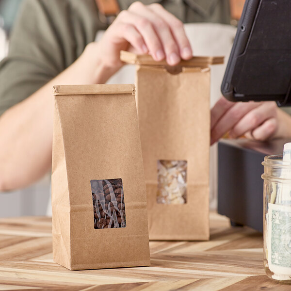 A person using a black tablet to pay for a brown Kraft Choice cookie bag on a counter.