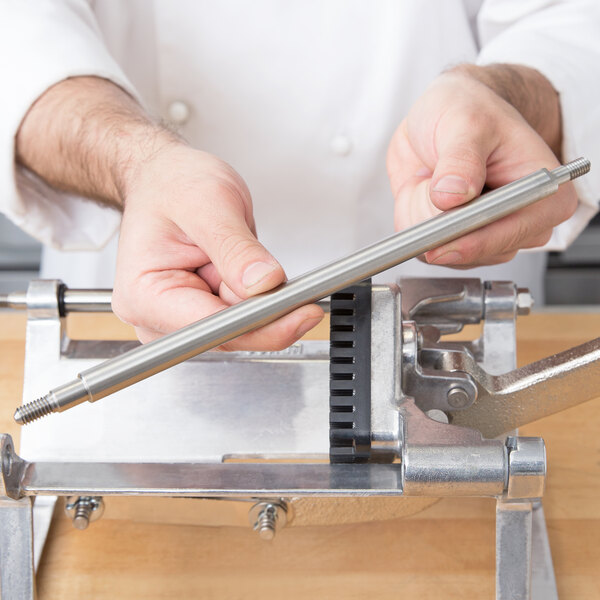 A person using a Nemco Guide Rod to cut fries.