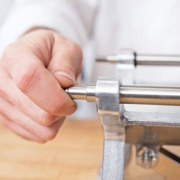 A hand using a Nemco guide rod to cut metal on a counter.