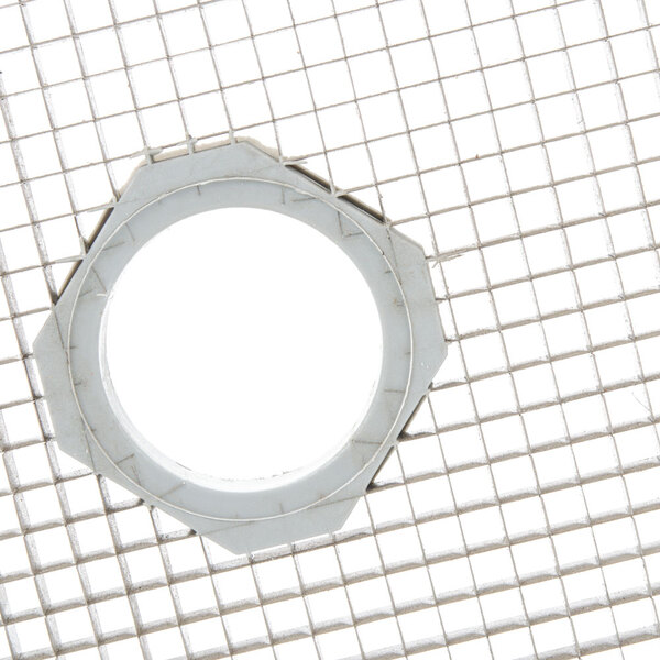A white circle on a metal grid with round holes.