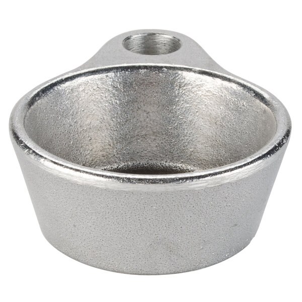 A silver metal cup with a small hole in the bottom, sitting on a table.