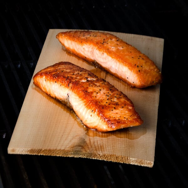Two grilled salmon fillets on wood plank