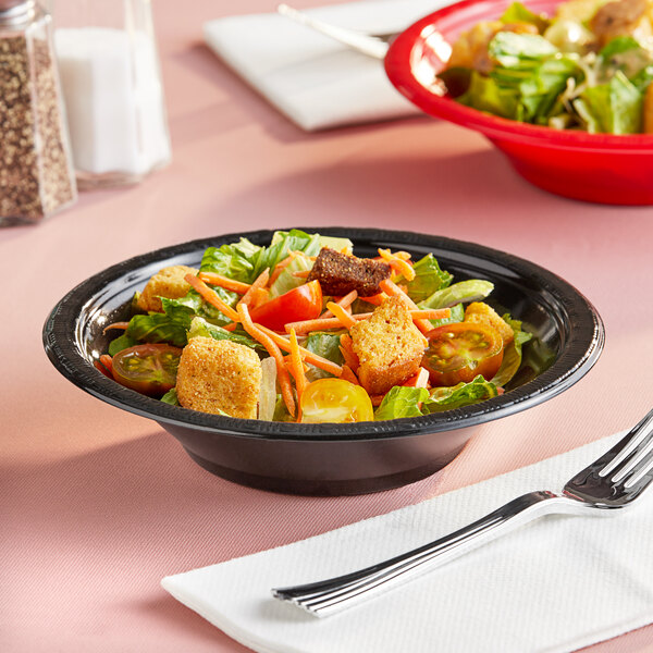 A bowl of salad with croutons and tomatoes on a table