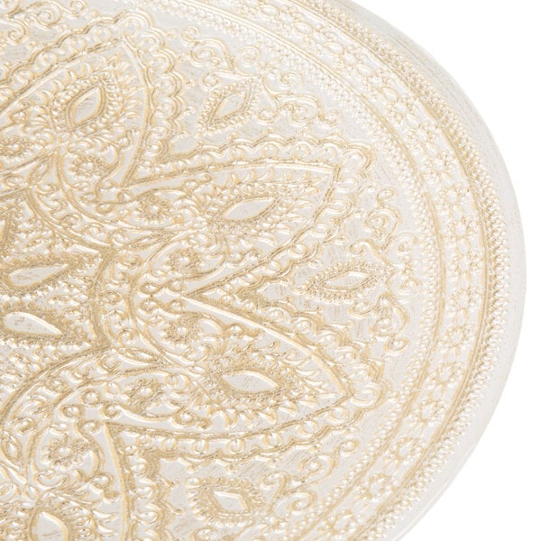 A close up of a gold glass Charge It by Jay charger plate with intricate designs.