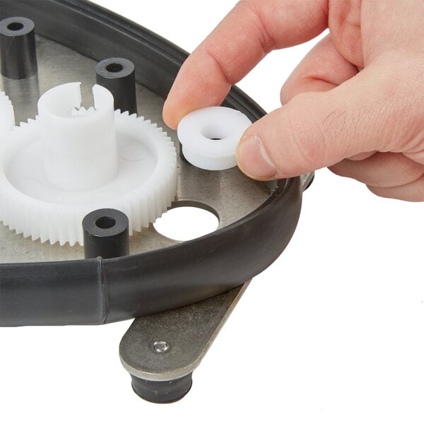 A hand holding Bar Maid white plastic bearing shafts with metal in the middle.