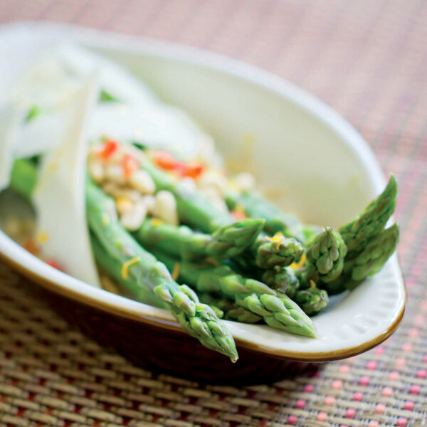 A Tuxton oval china rarebit bowl filled with asparagus and onions.