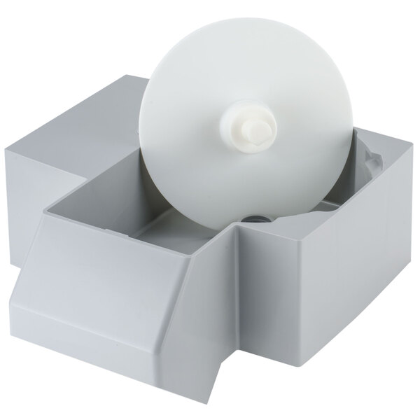 A white circular object in a box with a white plastic disc inside.