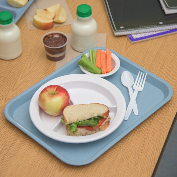 A Carlisle plastic fast food tray with a sandwich, carrots, celery, and a bottle of blue liquid on it.