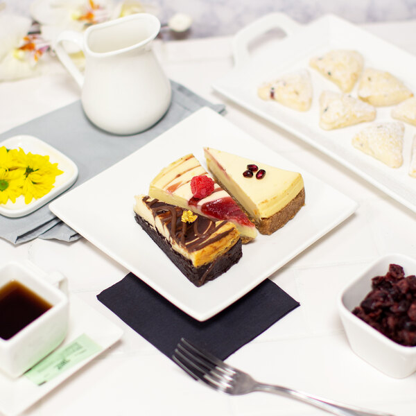 A 10 Strawberry Street white porcelain square plate with a slice of cheesecake on it.