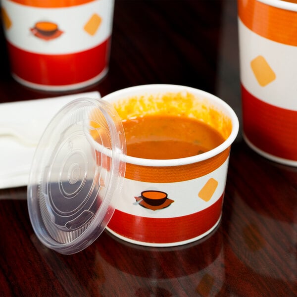 A Choice double poly-coated paper soup cup with a plastic lid filled with soup.