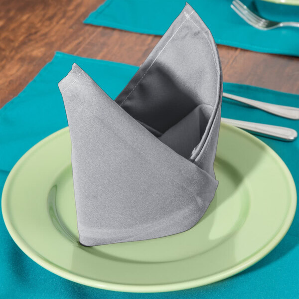 A folded Intedge gray polycotton napkin on a plate.