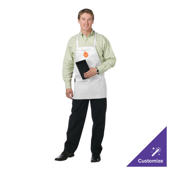 A man wearing a white Chef Revival apron holding a tablet in a professional kitchen.