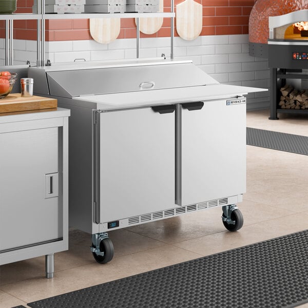 A stainless steel two-door refrigerated sandwich prep table with a raised cutting top and a deep cutting board.