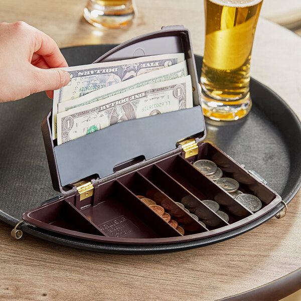 A Carlisle Money Maid round clip-on check presenter on a counter with money inside.