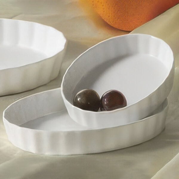 A close-up of a white fluted oval serving dish with two round objects inside.