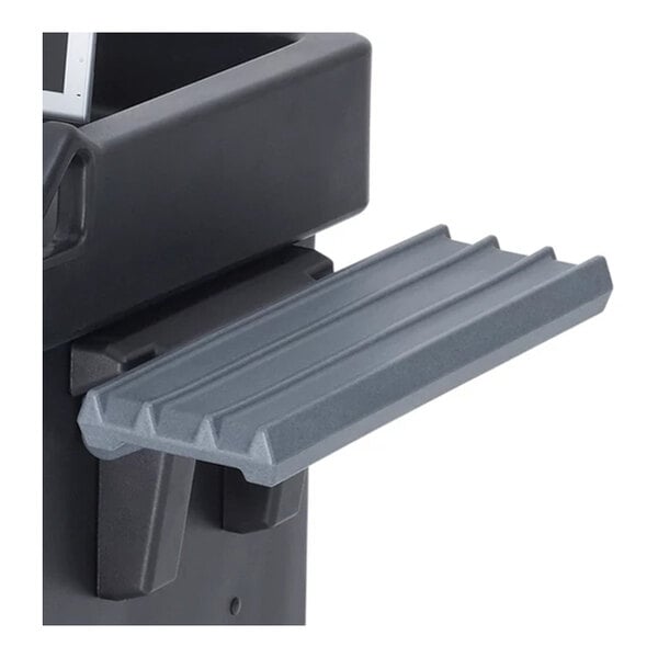 A close-up of a gray, ribbed tray rail attached to the side of a black cart.