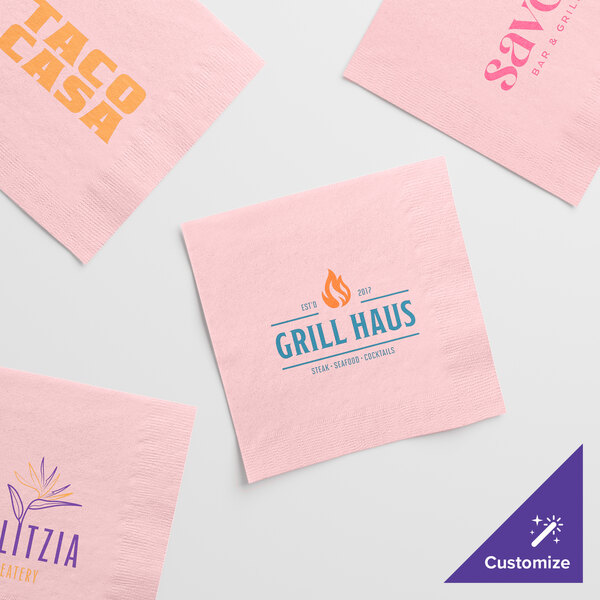 A set of pink customizable 2-ply beverage or cocktail napkins with various printed logos and designs.