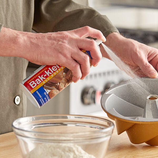 A person spraying Bak-Klene All Purpose Release Spray into a cake pan.