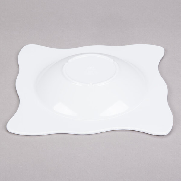 A white square bowl with a small wavy design on the edges.