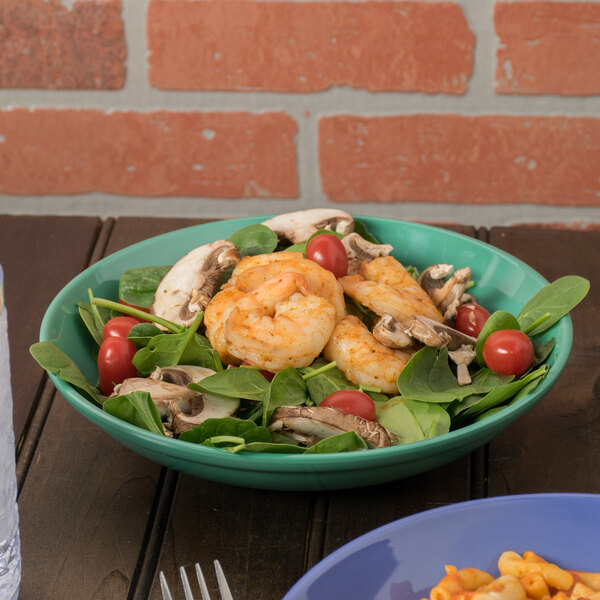 A bowl of salad with shrimp and tomatoes in a GET Diamond Mardi Gras melamine bowl.