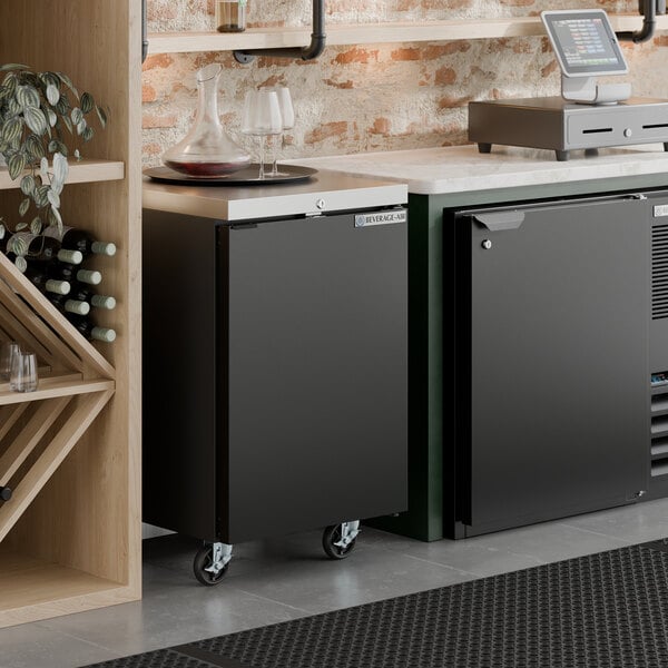 A black counter height solid door back bar refrigerator on wheels.